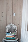 Shabby-chic chair with ornate backrest against board wall