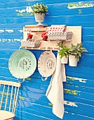 Hand-made shelf with pegs mounted on blue board wall