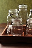 Several empty vintage flip-top preserving jars in a wooden crate