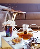 Glass teapot and glass teacup on coffee table