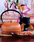 Orangefarbene Teekanne aus Gusseisen mit Deko in Rottönen