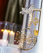 Romantisch verzierte Metall-Weihnachtskugel und goldfarbene Schlüssel an Türklinke aufgehängt