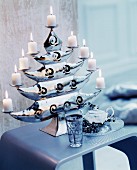 Eleganter glänzender Kerzenständer in Baumform mit brennenden weißen Stumpenkerzen