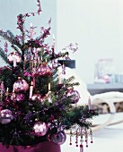 Romantisch geschmücktes Tannenbäumchen mit glänzenden Christbaumkugeln und brennenden Kerzen
