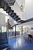 Woman walking up delicate metal staircase in loft apartment in shades of grey