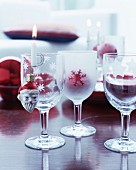 Lit candle in candle holder on edge of etched wine glass and Christmas tree bauble