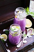 Blueberry smoothies with grated coconut, lemon, mint and silver spoons