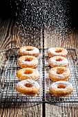 Freshly baked doughnuts being dusted with icing sugar
