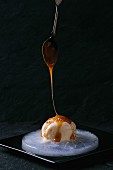 Caramel and hazelnut butter ice cream with pouring caramel on a plate of ice