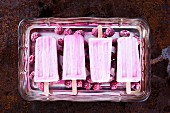 Raspberry cheesecake ice cream sticks with frozen raspberries on a silver tray
