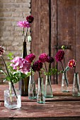 Blumendeko in Vasen auf Holztisch