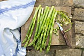 Green asparagus on a chopping board with a knife