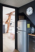 Fridge under staircase spandrel, clock on wall and view into living room