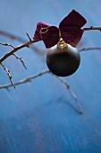 Black Christmas-tree bauble with felt ribbon on bare branch