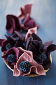 Blue-painted larch cones in folds of felt in berry shades