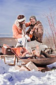 Man and woman with guitar during a winter picnic in a snowy landscape
