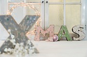 Shabby-chic ornamental letters spelling XMAS in front of window