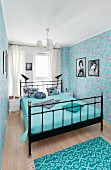 Metal bed and floral wallpaper in blue bedroom