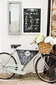 Fahrrad mit Korb voller Blumen und Werbeschild für Restaurant