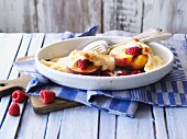 Baked peaches with raspberries in a baking dish