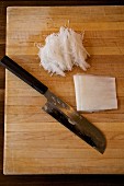 Fein geschnittener Daikon-Rettich im japanischen Stil auf Holzschneidebrett mit japanischem Messer