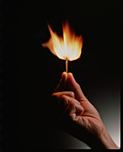 Hand holds a match ignited