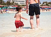 Man and boy walking in sea at the beach