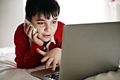 Boy using a mobile phone and laptop