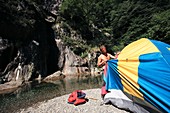 Man erecting a tent by a river