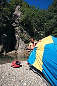 Man erecting a tent by a river