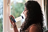 Woman using an inhaler with spacer