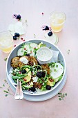 Crispy potato cakes on a bed of vegetables with avocado, blackberries and pomegranate seeds