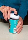 Elderly woman opening a tin