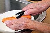 Elderly man peeling a carrot