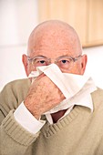 Elderly man blowing his nose