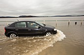 A motorist travels through flood waters