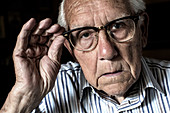 Elderly man adjusting his glasses