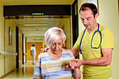 Hospital doctor assisting elderly woman