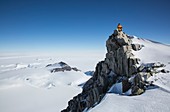 A climber on a rocky peak in Antarctica