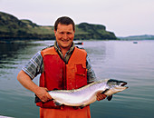 Man holding salmon at a Scottish salmon farm
