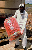 Worker in protective clothing unloading asbestos
