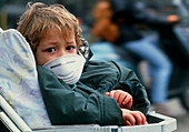 Child in buggy with air pollution face mask