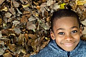 Smiling boy lying on autumn leaves