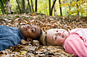 Smiling children lying on autumn leaves