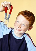 Boy lifting paperclips with a magnet