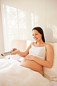 Pregnant woman watching TV in bed