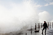Man on sea front with crashing waves