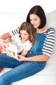 Mother reading book with daughter