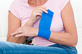 Woman putting bandage on wrist