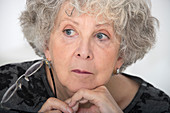 Woman with grey hair holding eyeglasses